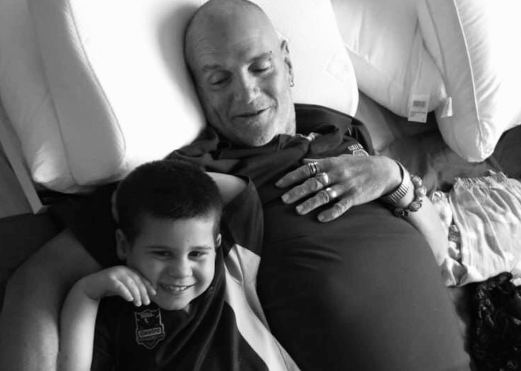 Black and white picture of a loving grandad lying down with his smiling grandson.
